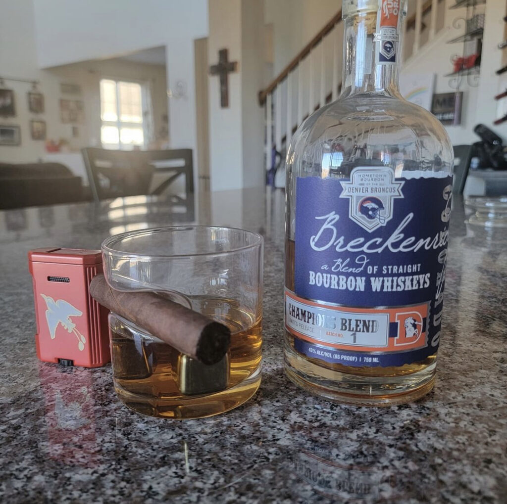 @wineaurorasouth Denver Broncos Blend Blue Edition Breckenridge Bourbon Whiskey bottle with whiskey glass and cigar on counter